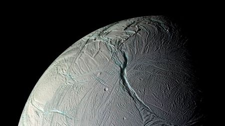 A close up of a gray planet with various streaks and ditches in its surface. 