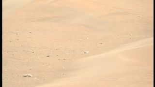 Reddish-tan sand is seen with a few rocks at the base of a large ripple in a photo taken by NASA's Perseverance Mars rover