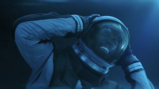a man grimacing in pain inside a spacesuit